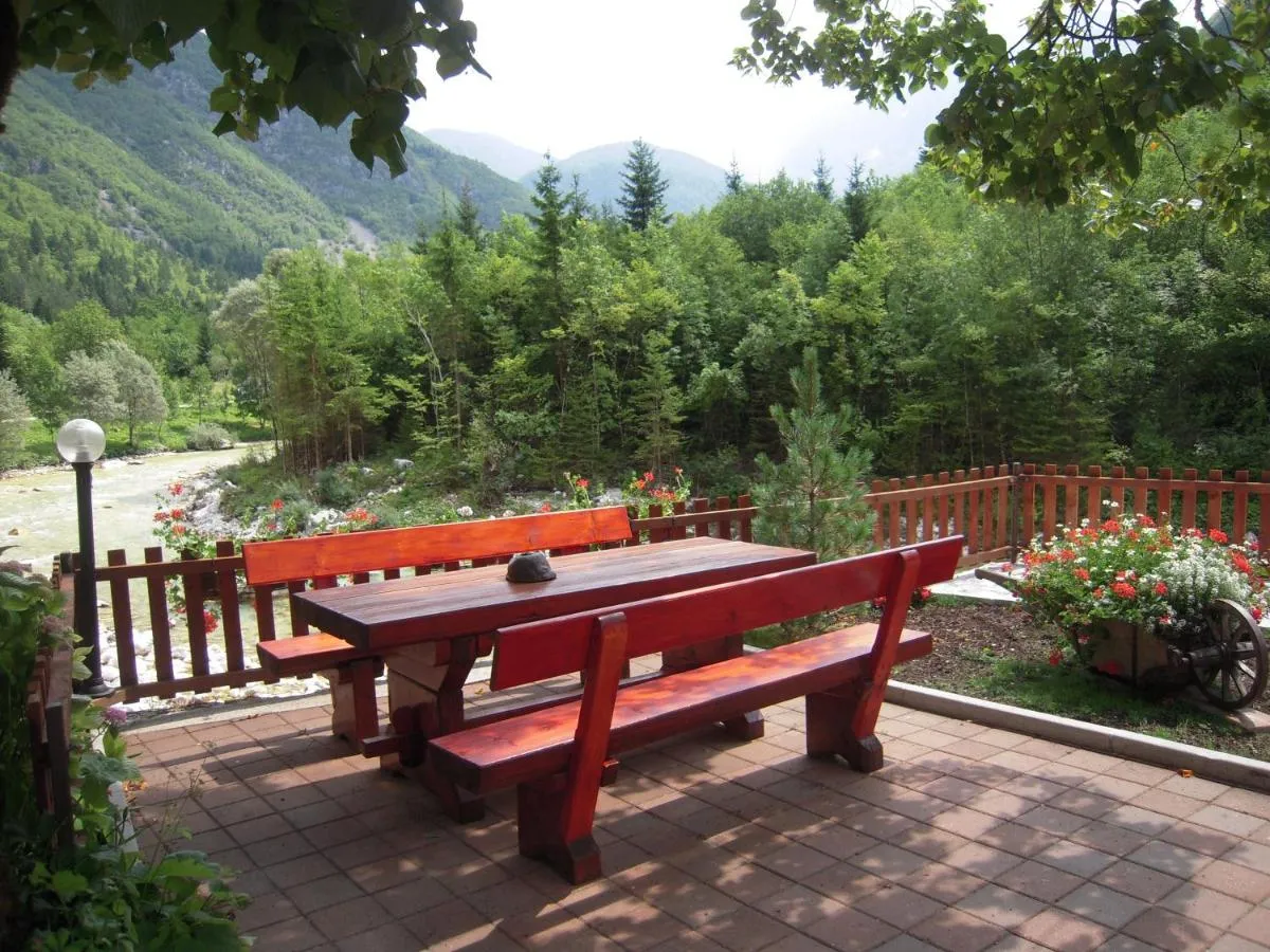 Lesena miza in klopi na vrtu, za ograjo Soča in gore